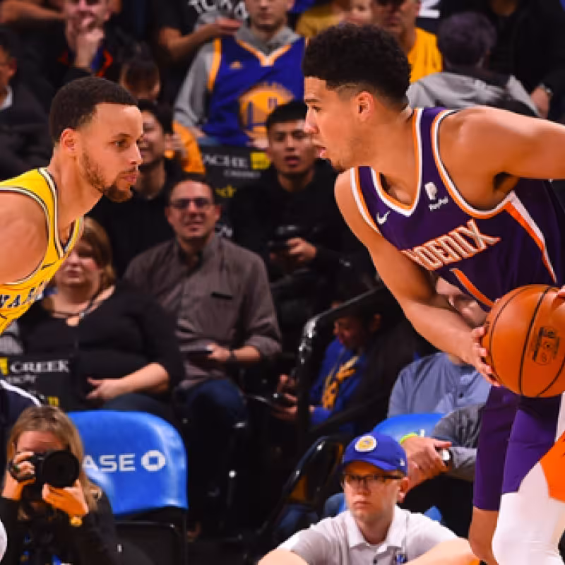 Devin Booker, ante Stephen Curry durante el Suns-Warriors.