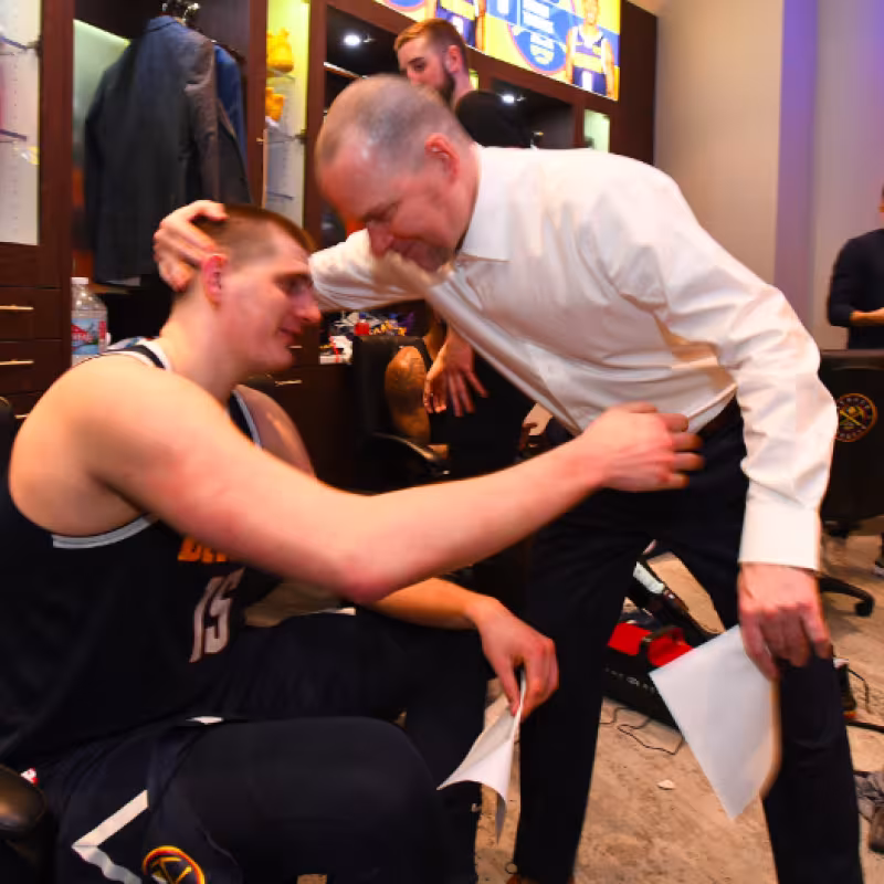 Nikola Jokic es felicitado por su entrenador Michael Malone.