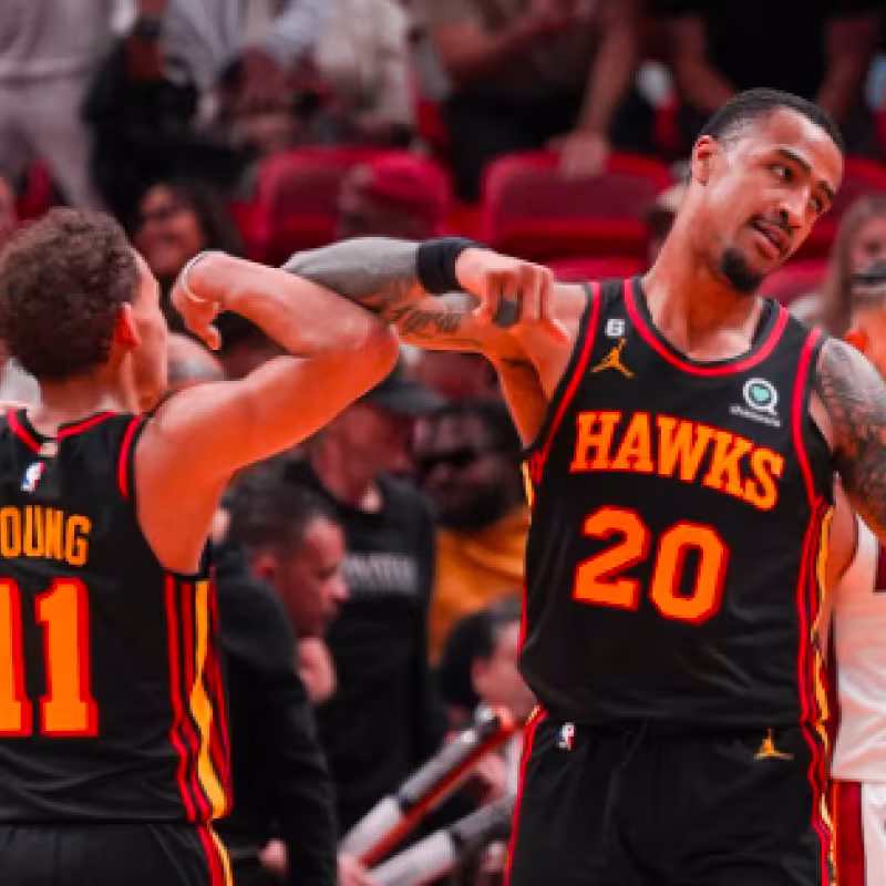 John Collins y Trae Young celebran una canasta ante los Heat. 