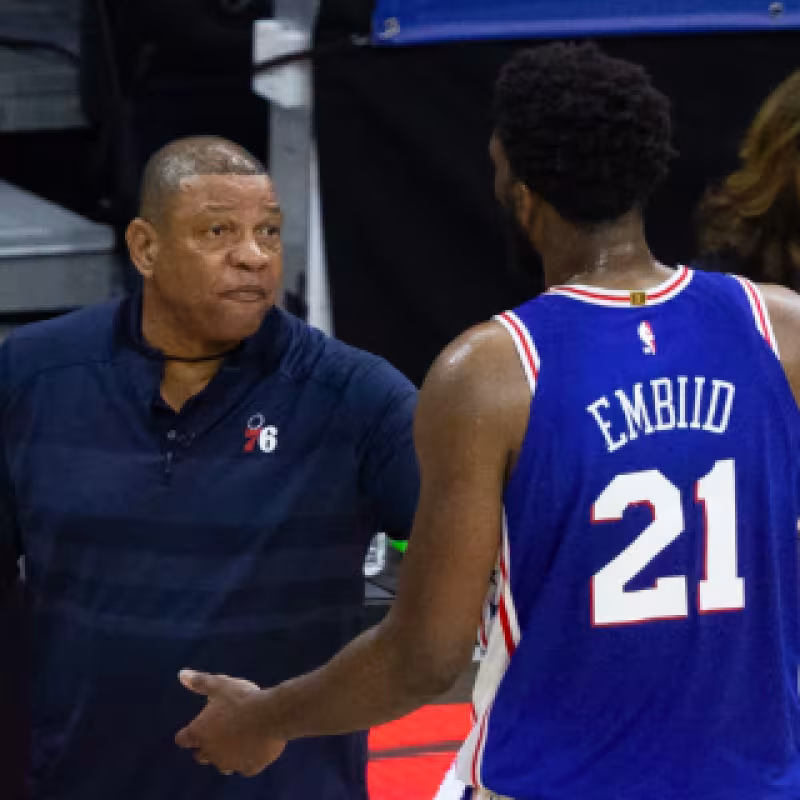 Doc Rivers, junto a Joel Embiid.