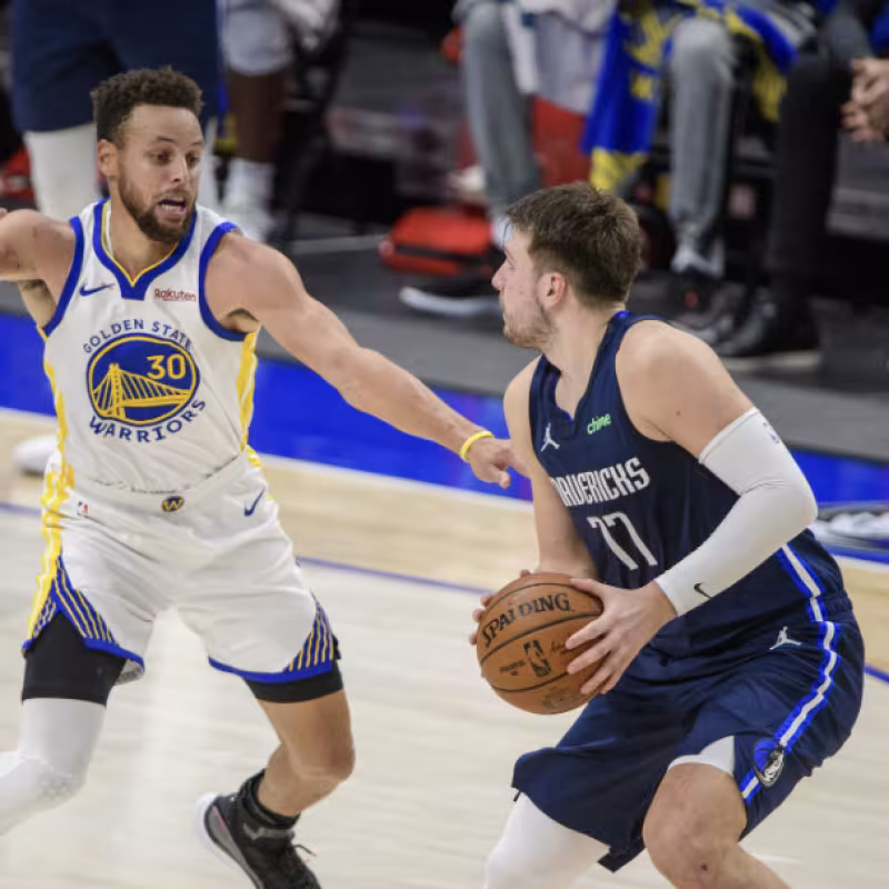 Luka Doncic attempting a shot against Stephen Curry's defense