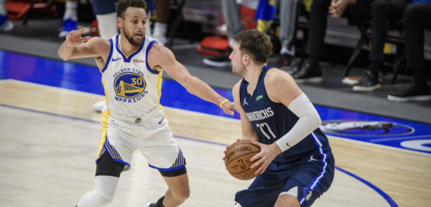 Luka Doncic attempting a shot against Stephen Curry's defense